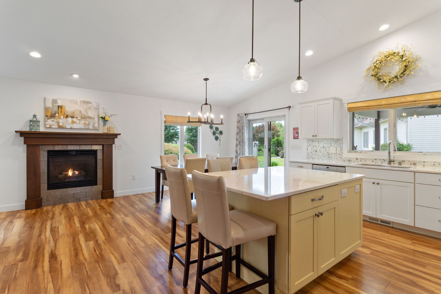 Interior photo showing kitchen island, dining room, and fireplace seamlessly connected