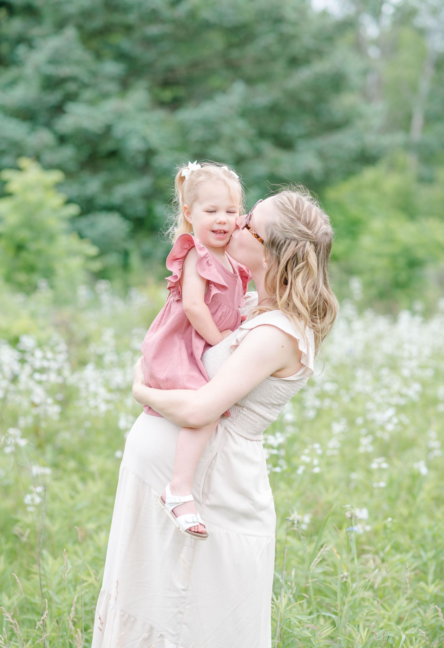 Normal, Illinois mom in a white dress kissing her daughter in a pink dress on the cheek during a maternity session by Julie Loy Photography