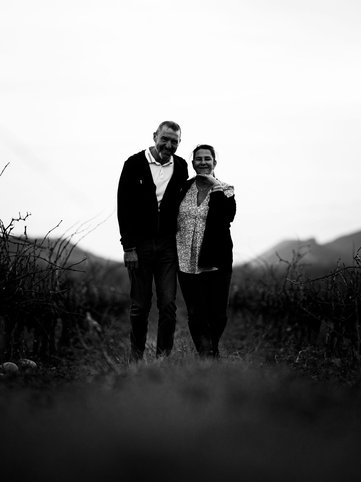 Photographie noir & blanc de couple dans les champs avec une ambiance naturelle