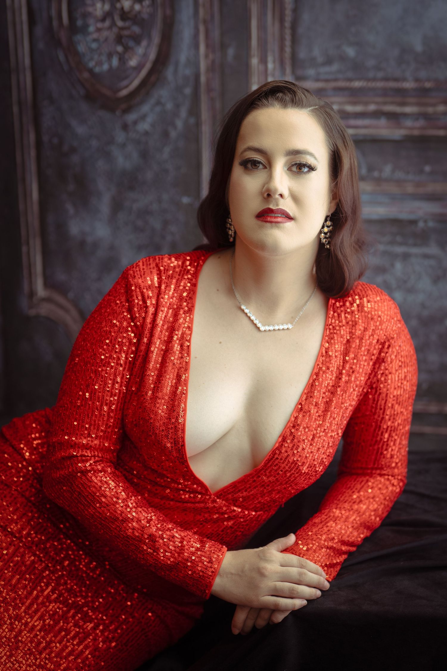 Glamour portrait series in sparkling red sequin dress against dark backdrop.