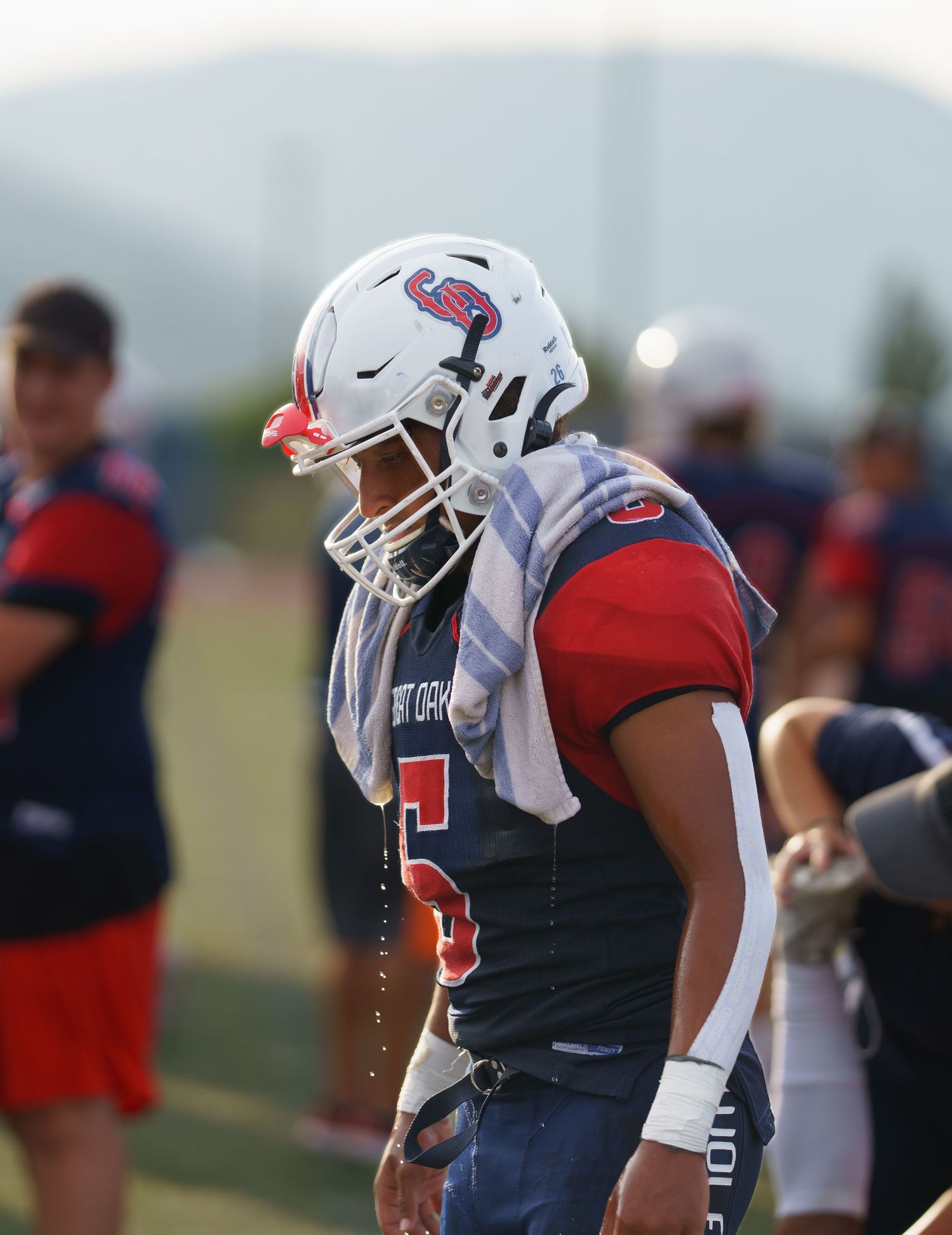 Football players in red and white uniforms practicing on a field during training camp.