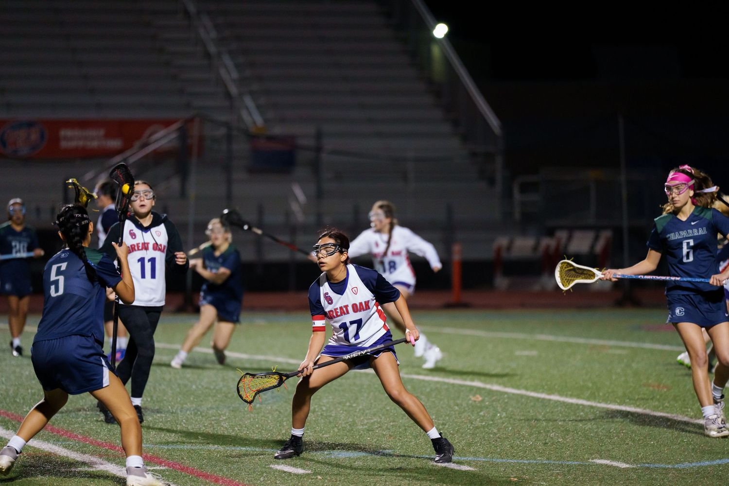 Tennis players practicing drills and techniques on a dark outdoor court at night under stadium lights.