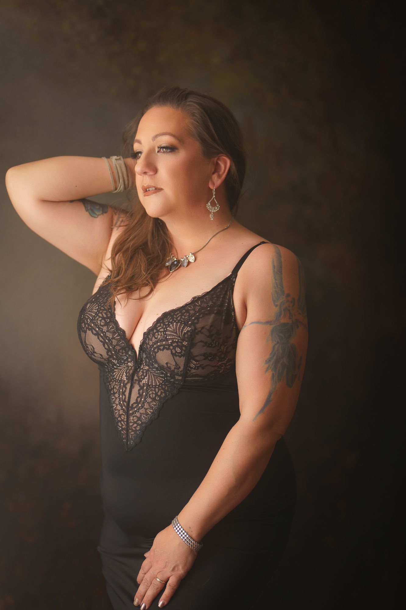 Dramatic studio portrait series featuring lace lingerie against dark background.
