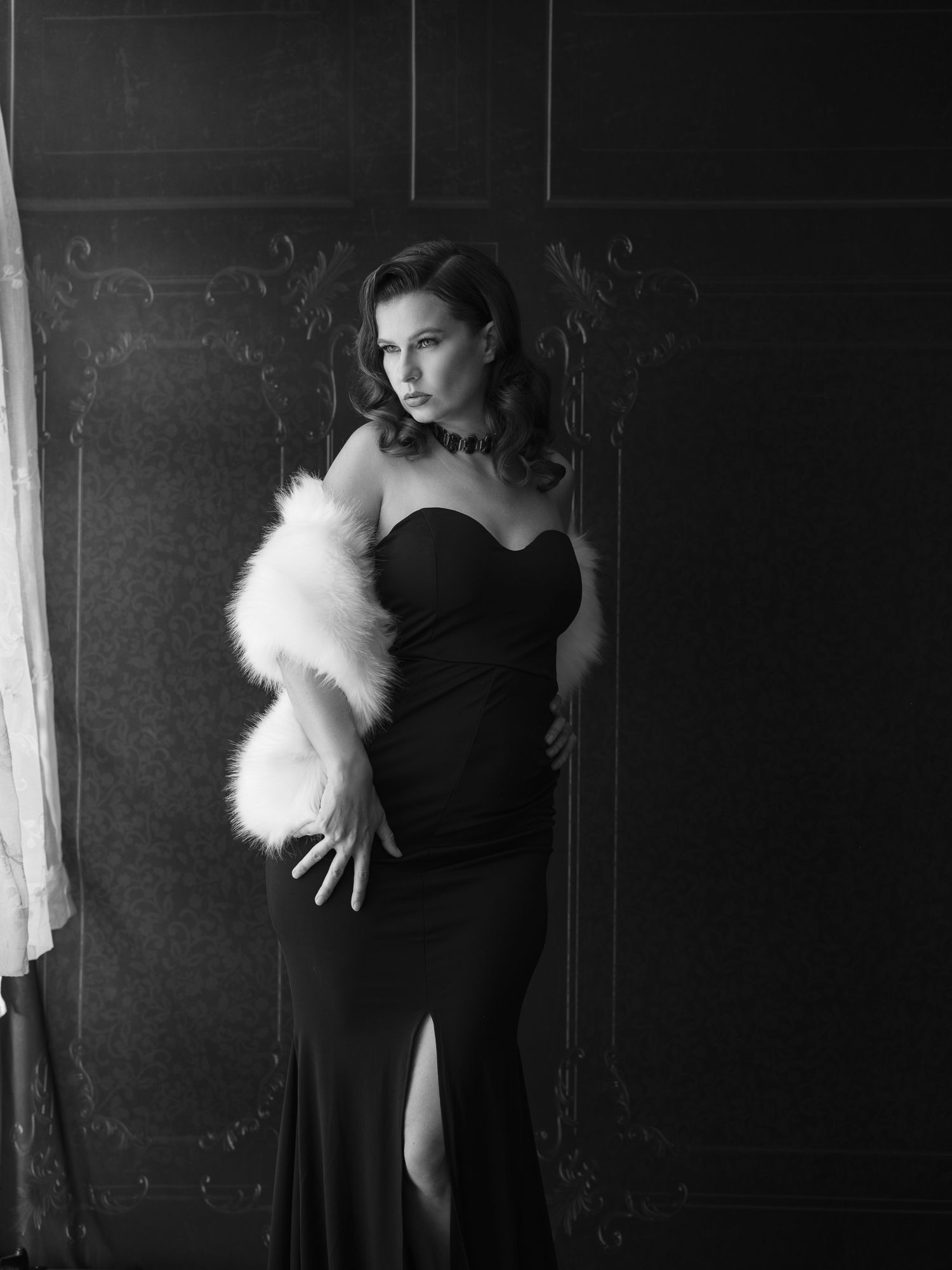 Vintage style portraits featuring a black dress and white feather boa in moody lighting.