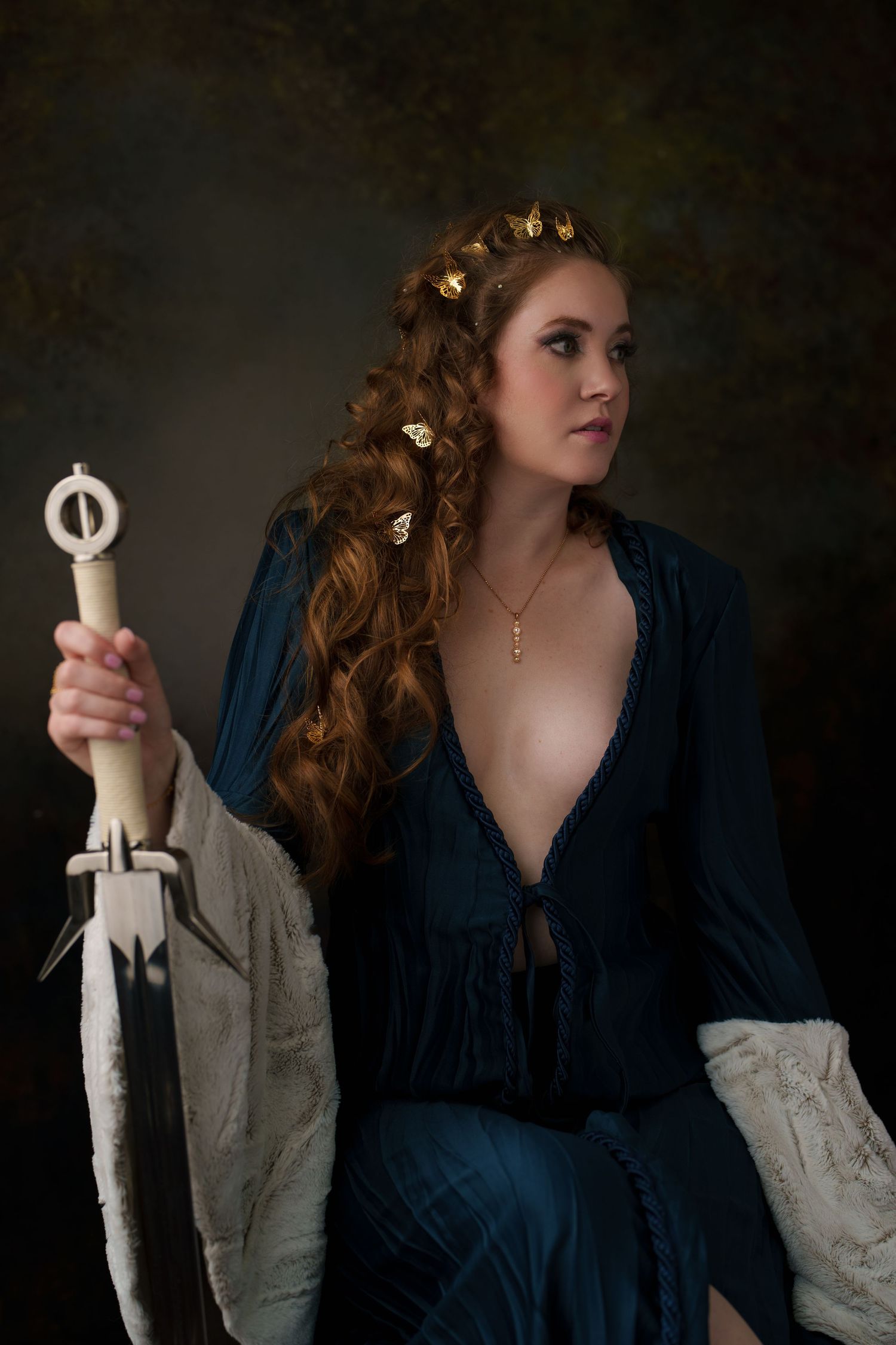 A dramatic portrait series showing a medieval inspired look with a dark blue dress and gold hair accessories.