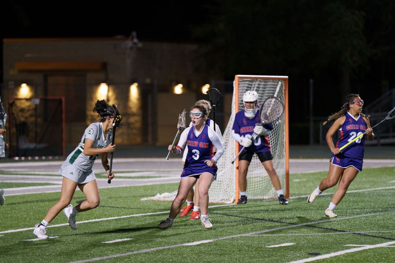 Field hockey players lunge forward in a synchronized training drill on an artificial turf field.