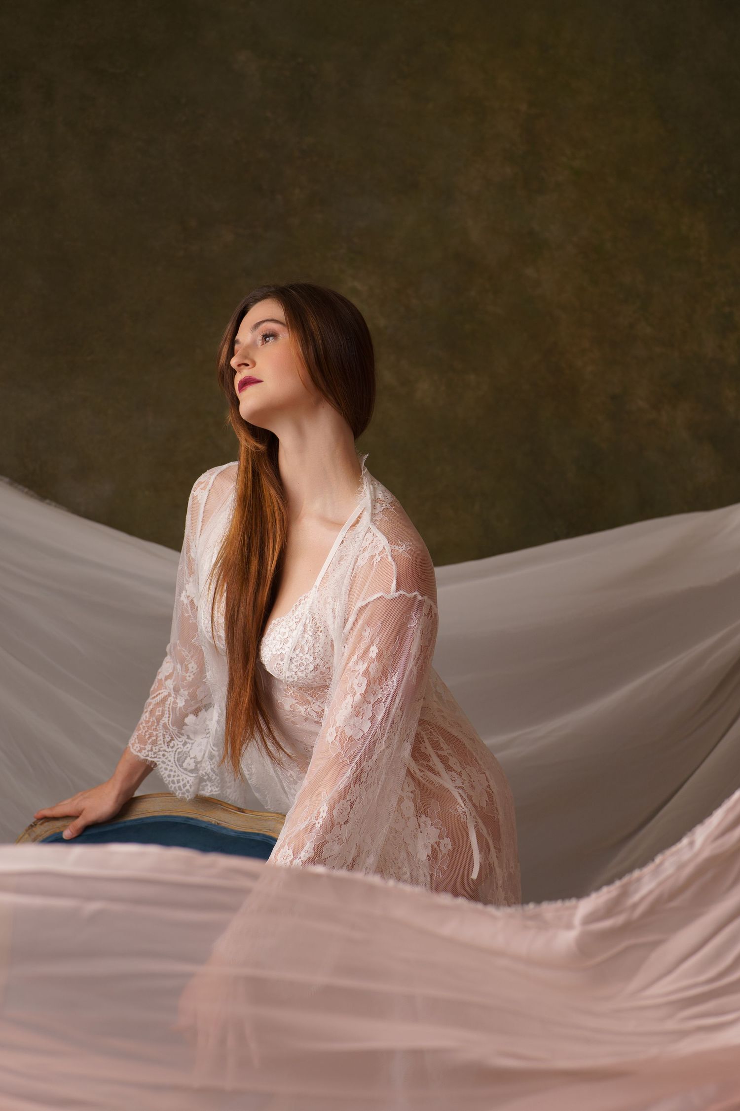 Romantic boudoir photography with flowing white lace robe against neutral backdrop.