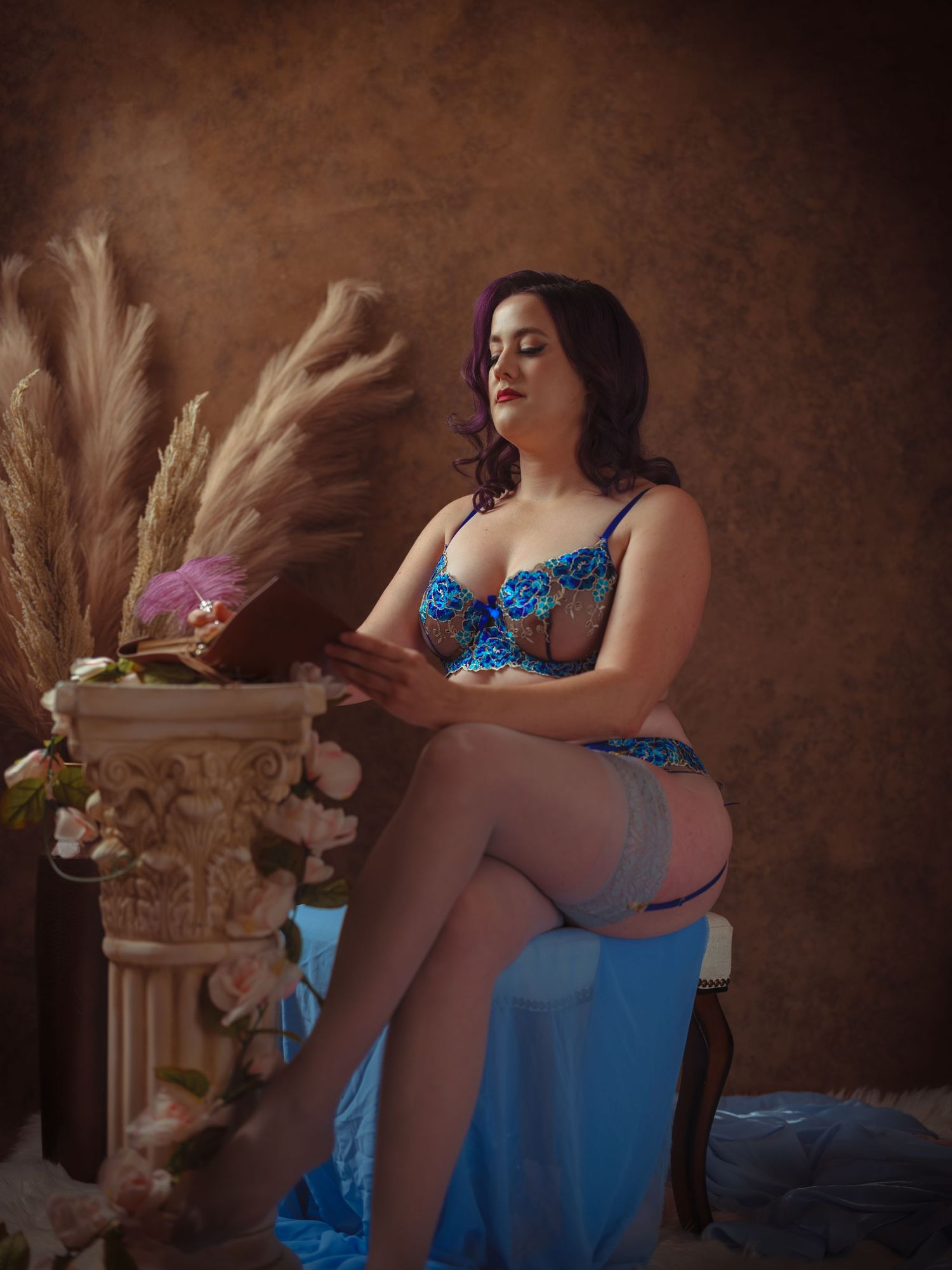 Dramatic boudoir photography with blue dress and vintage decor against dark textured background.