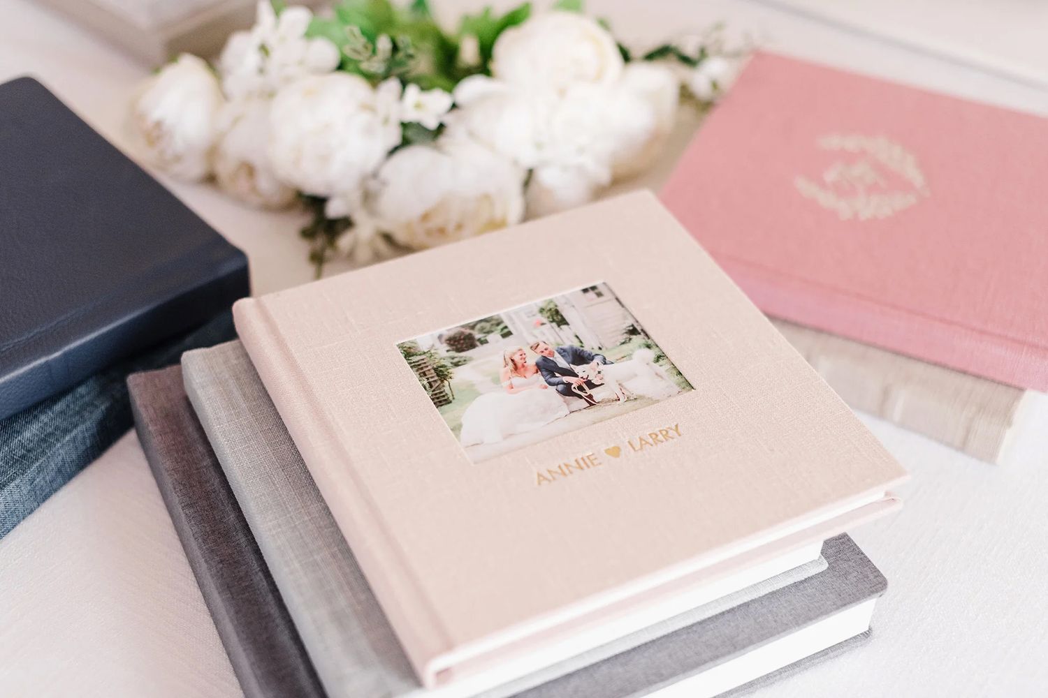 Collection of pink and white wedding photo albums with floral decorations.