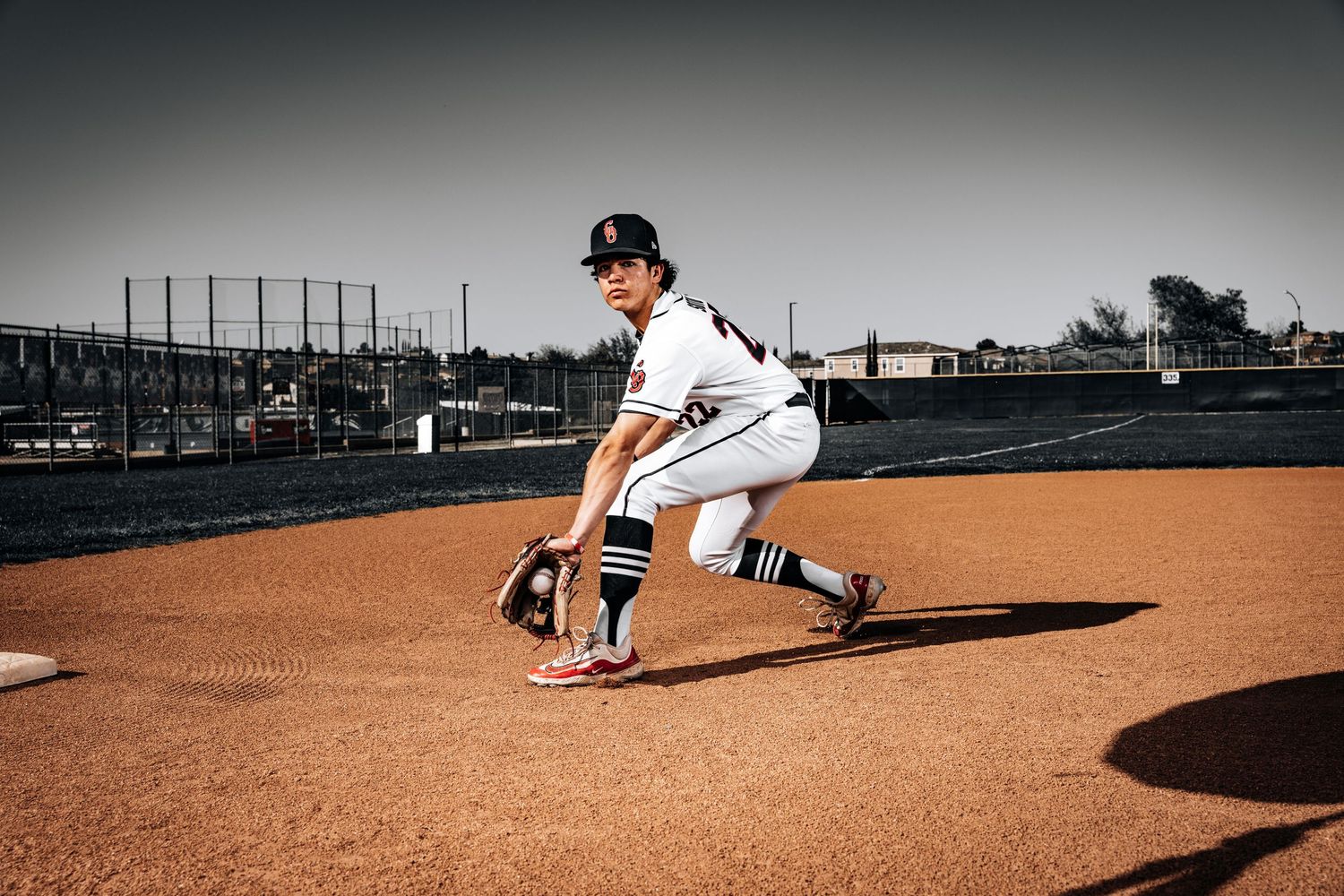 Baseball player stretches and warms up on the pitcher's mound before a game at an outdoor stadium.