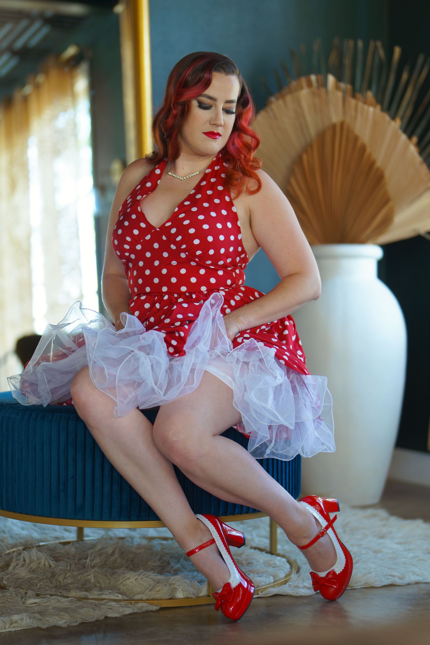 Retro pinup style photos in polka dot dress and white petticoat with red heels.