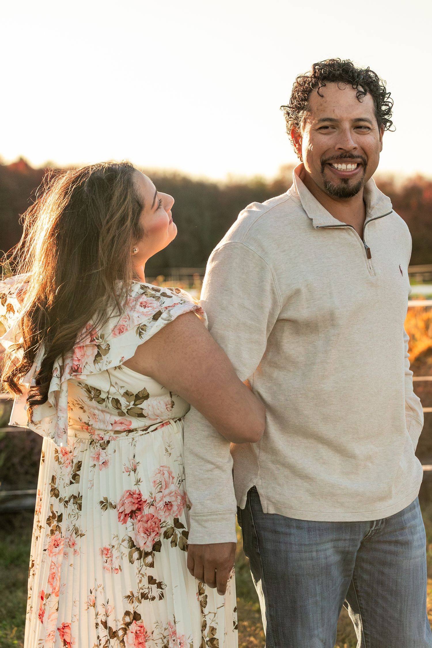 A couple in casual attire shares intimate moments at sunset in a rustic outdoor setting.