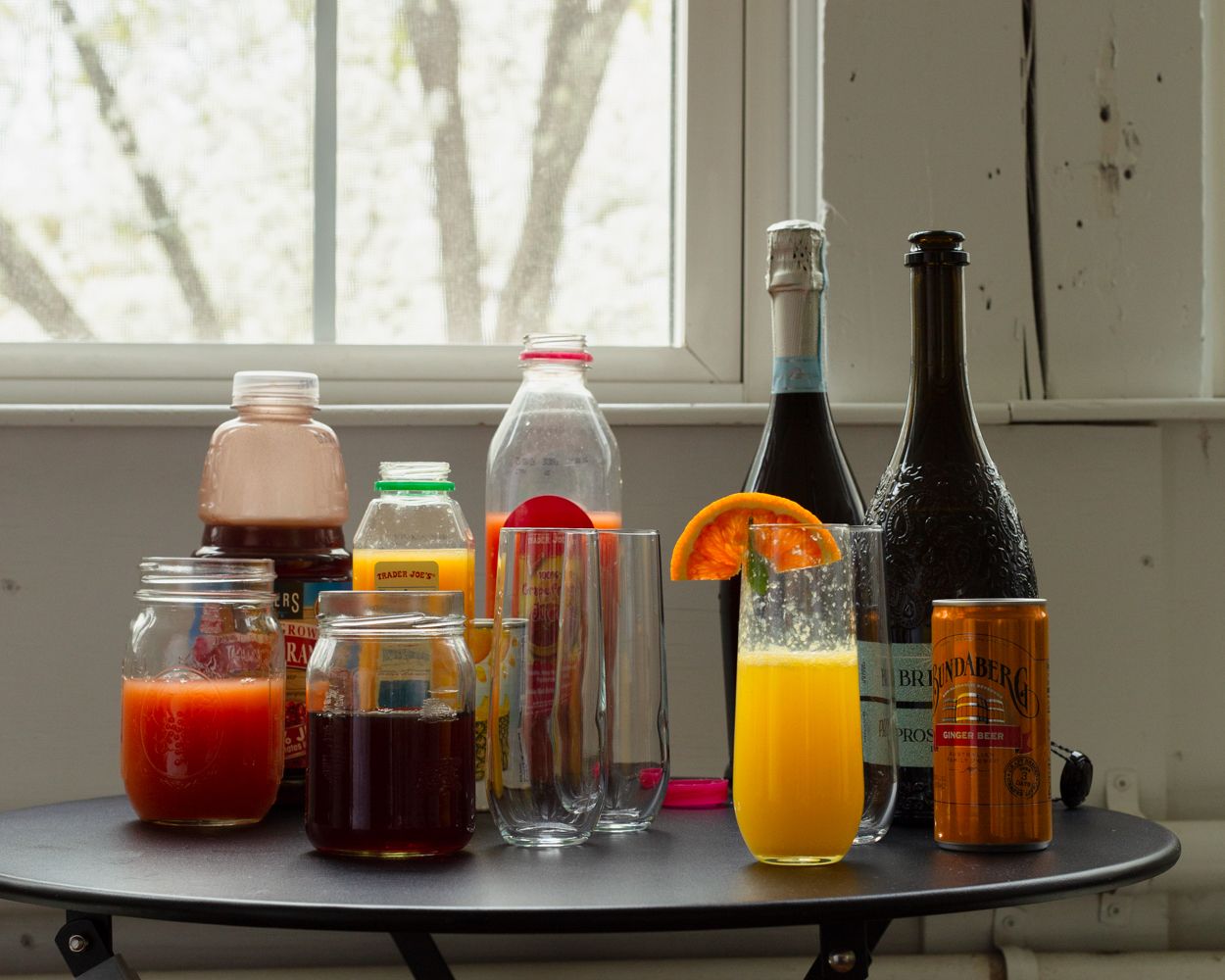 Assorted beverages including juice, mimosa, and sparkling wine on a round table.