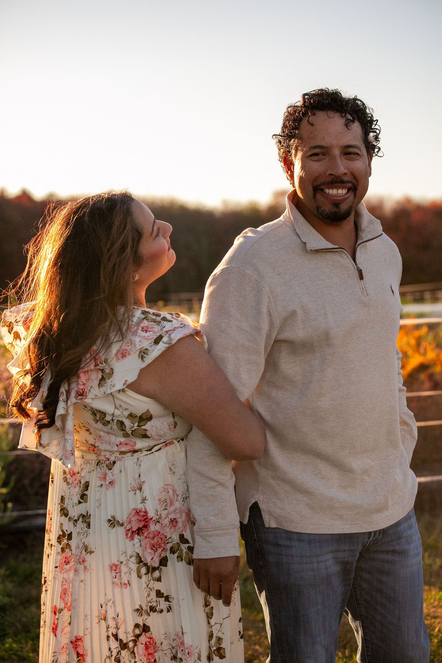 A couple shares a joyful moment together at sunset in a natural outdoor setting.