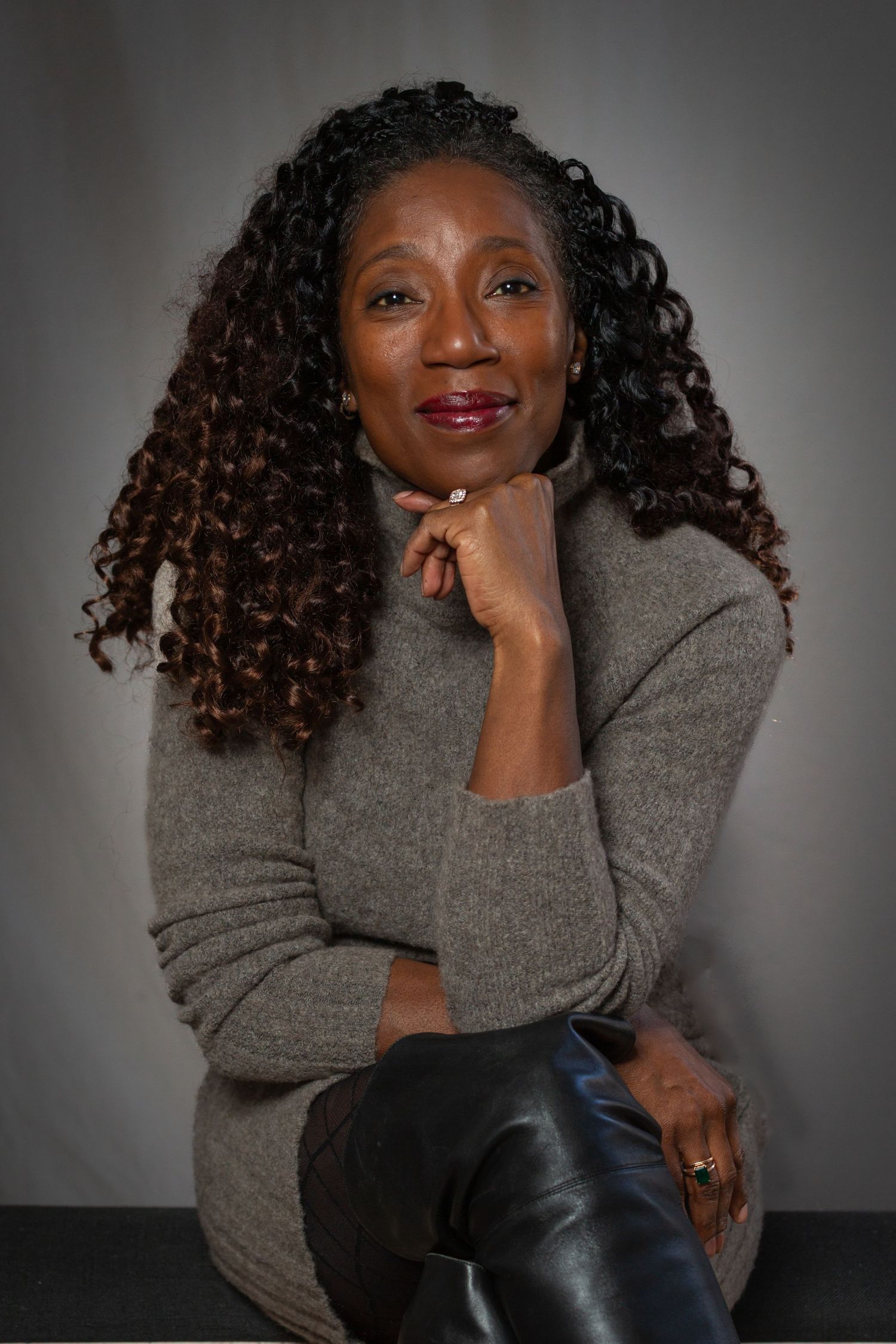 Professional portrait series showing joyful expressions in a grey sweater against dark background.