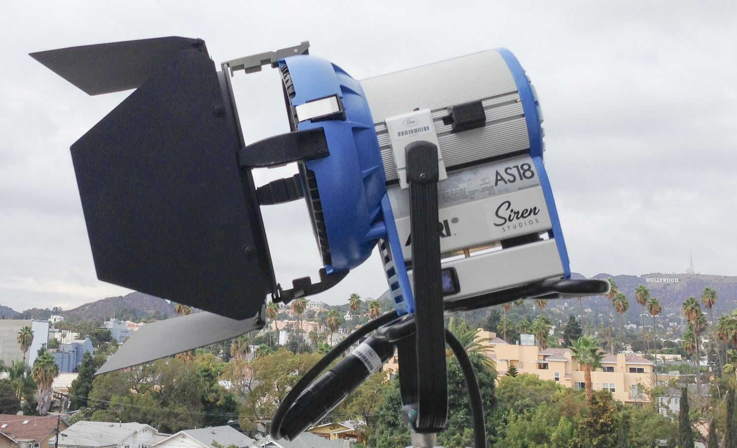 Professional lighting equipment and barndoors mounted against cloudy sky.