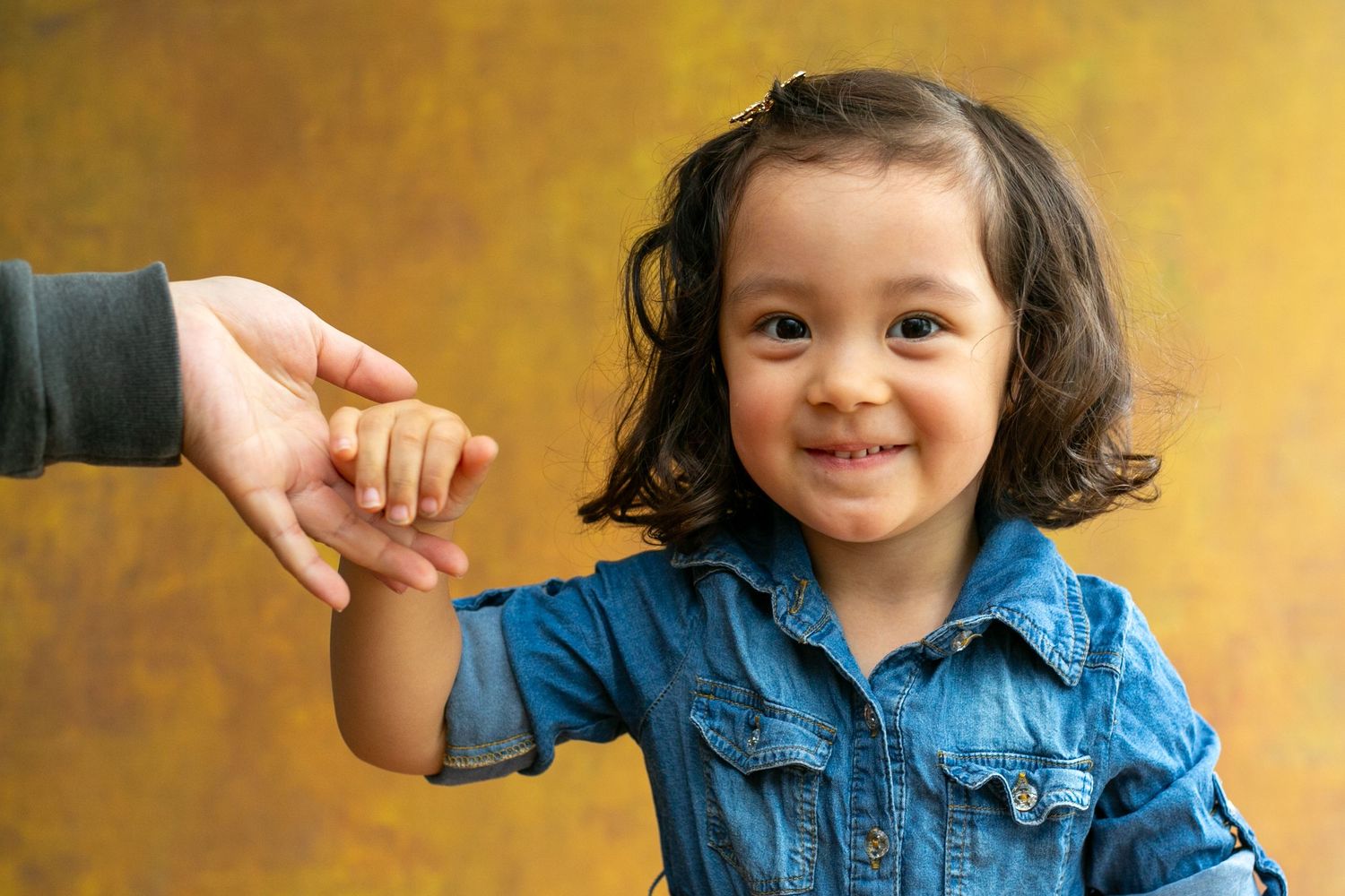 A series of connected photos showing a young child in a denim jacket making various playful expressions.