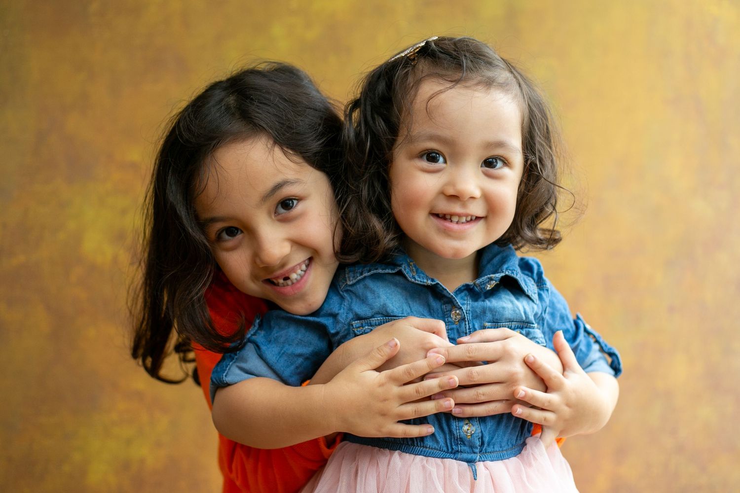 Two children share playful hugs and laughter in a series of warm-toned portrait photographs.