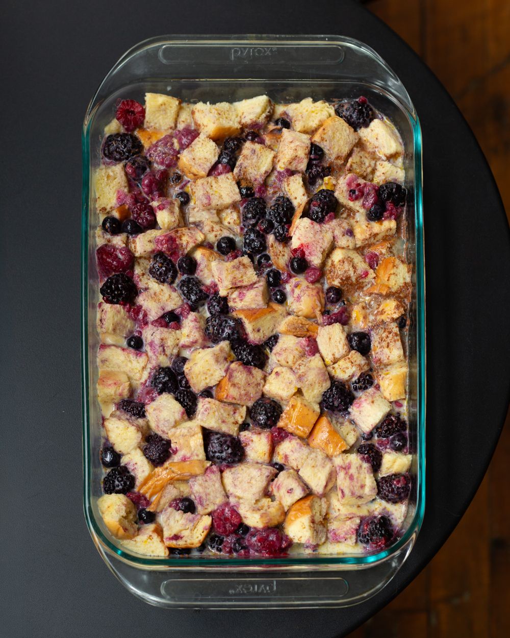 Baked blackberry bread pudding in a glass dish, golden cubed bread with fresh blackberries in creamy custard.