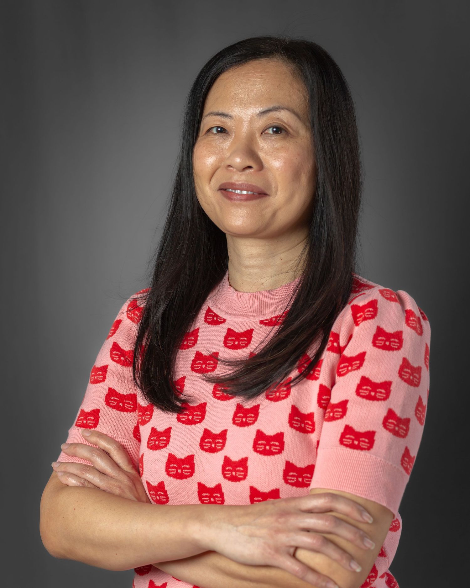 Person wearing a pink shirt with red cat pattern poses against gray background in a photo series.