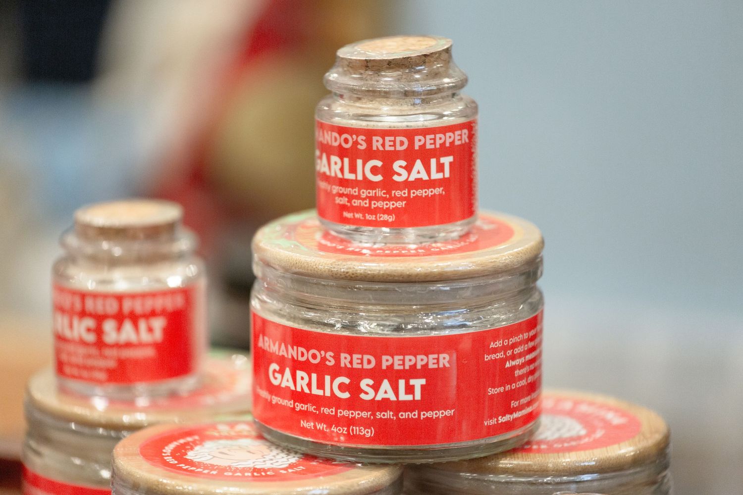 Three jars of Armando's Red Pepper Garlic Salt seasoning stacked on a display surface.