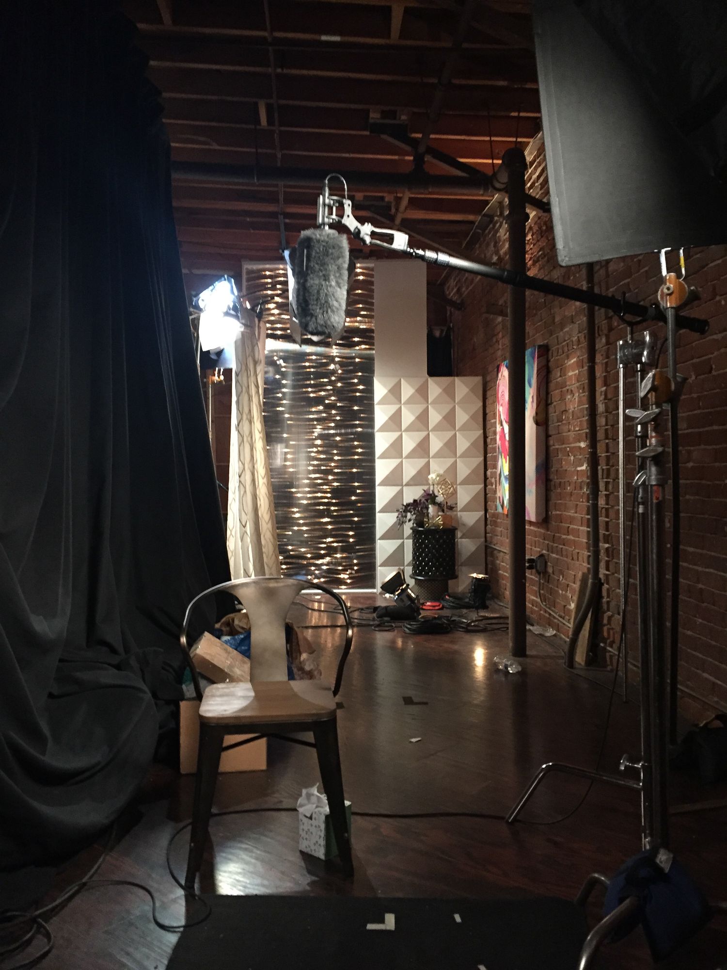 Dark studio photography setup with lighting equipment and black curtains.
