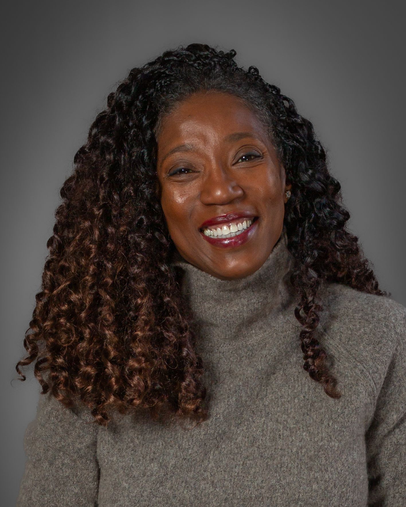 A person wearing a gray turtleneck sweater shows off their curly hair and bright smile in a series of expressive poses.