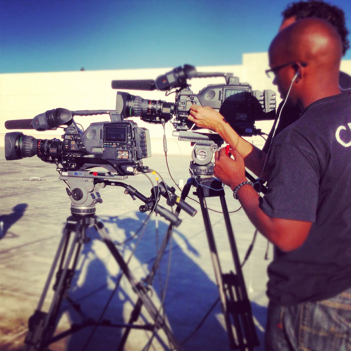 Row of professional video cameras set up on tripods for outdoor filming.