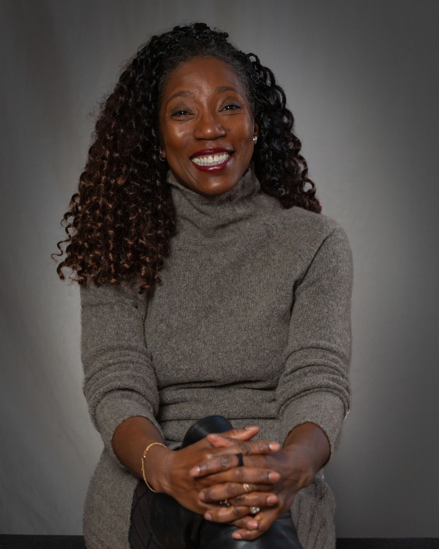 A series of photos showing someone in a gray turtleneck sweater expressing joyful emotions with natural curly hair.