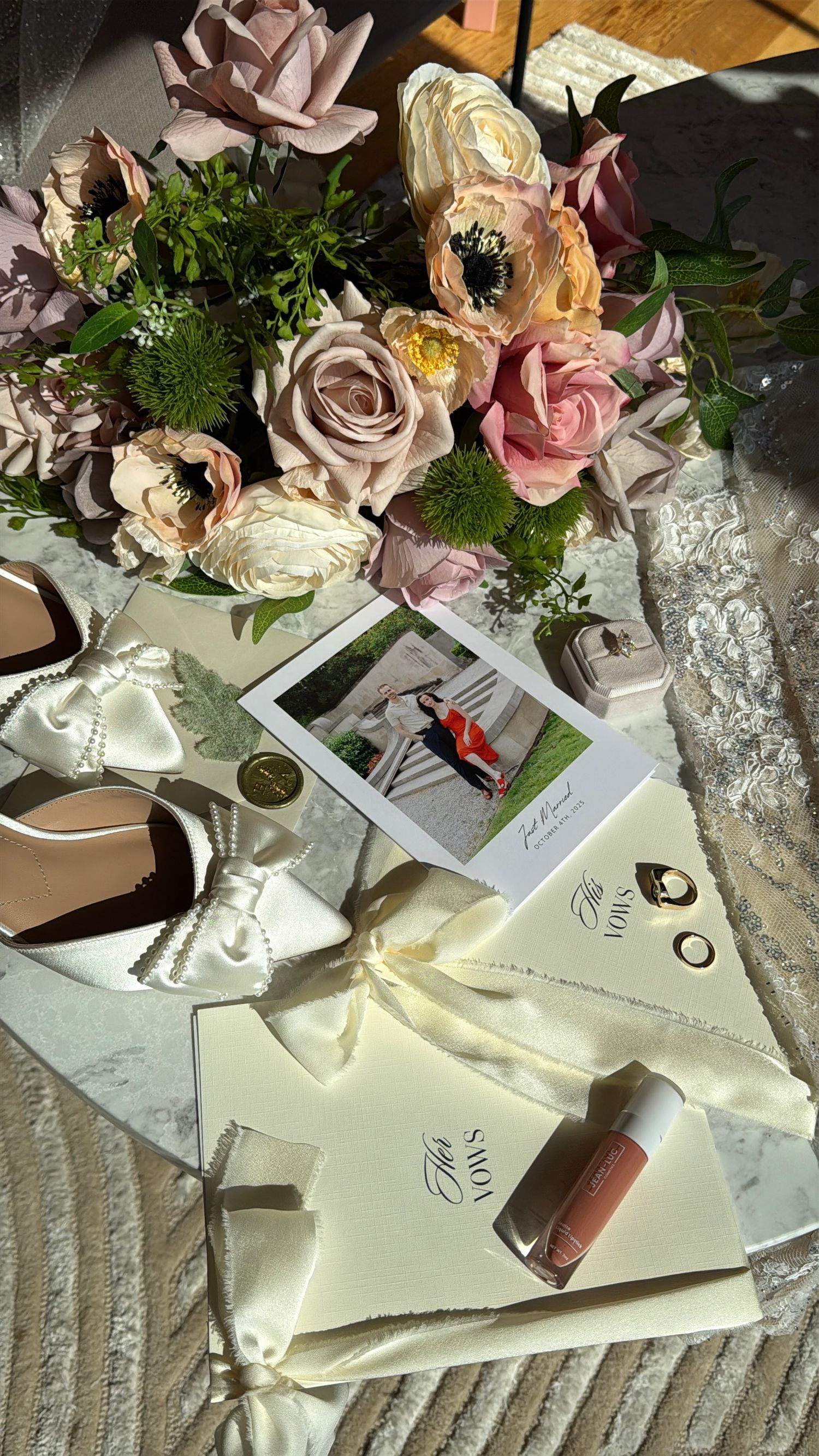 Wedding table settings with pink roses, envelopes, and decorative elements create an elegant reception atmosphere.