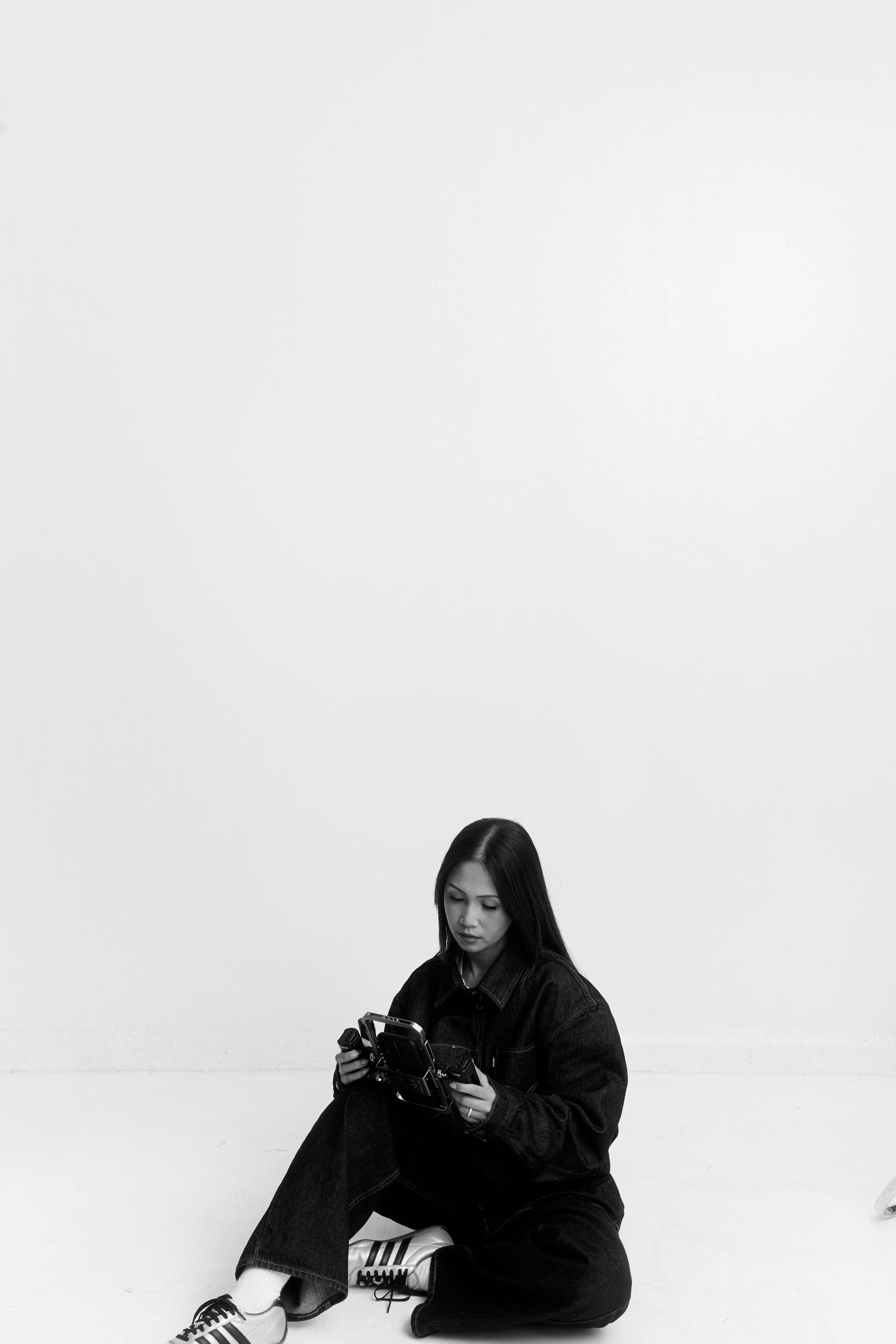 Monochromatic series showing figure in dark clothing with camera against white backdrop.