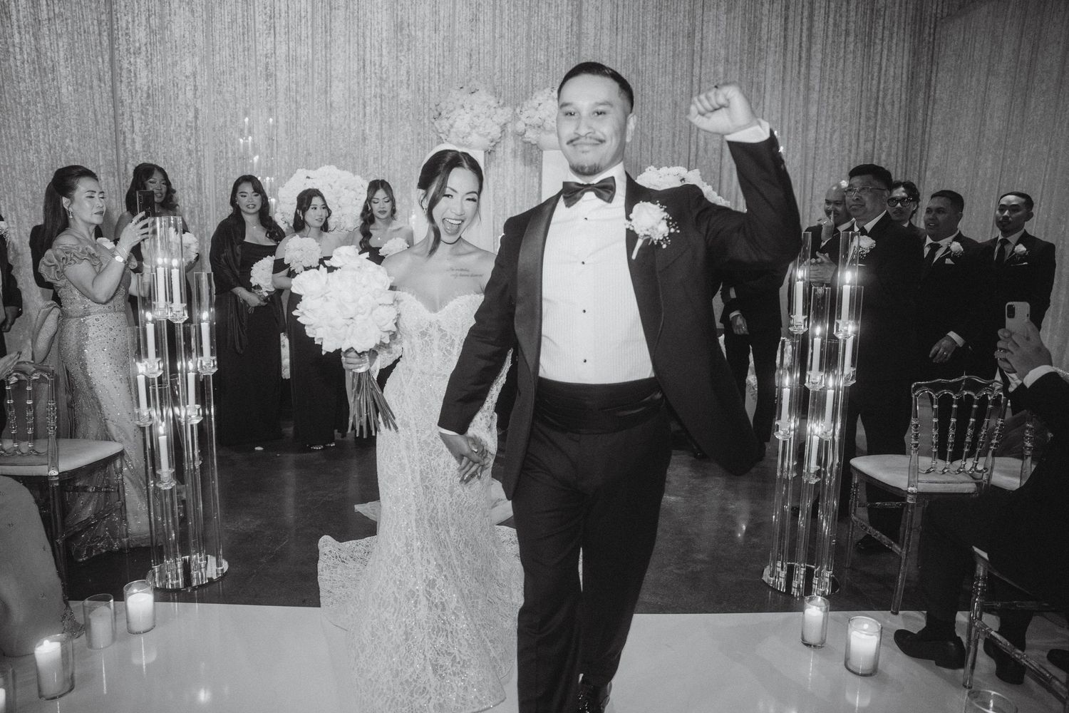 Elegant balck and white photo displaying bride and groom walking down the altar in celebration