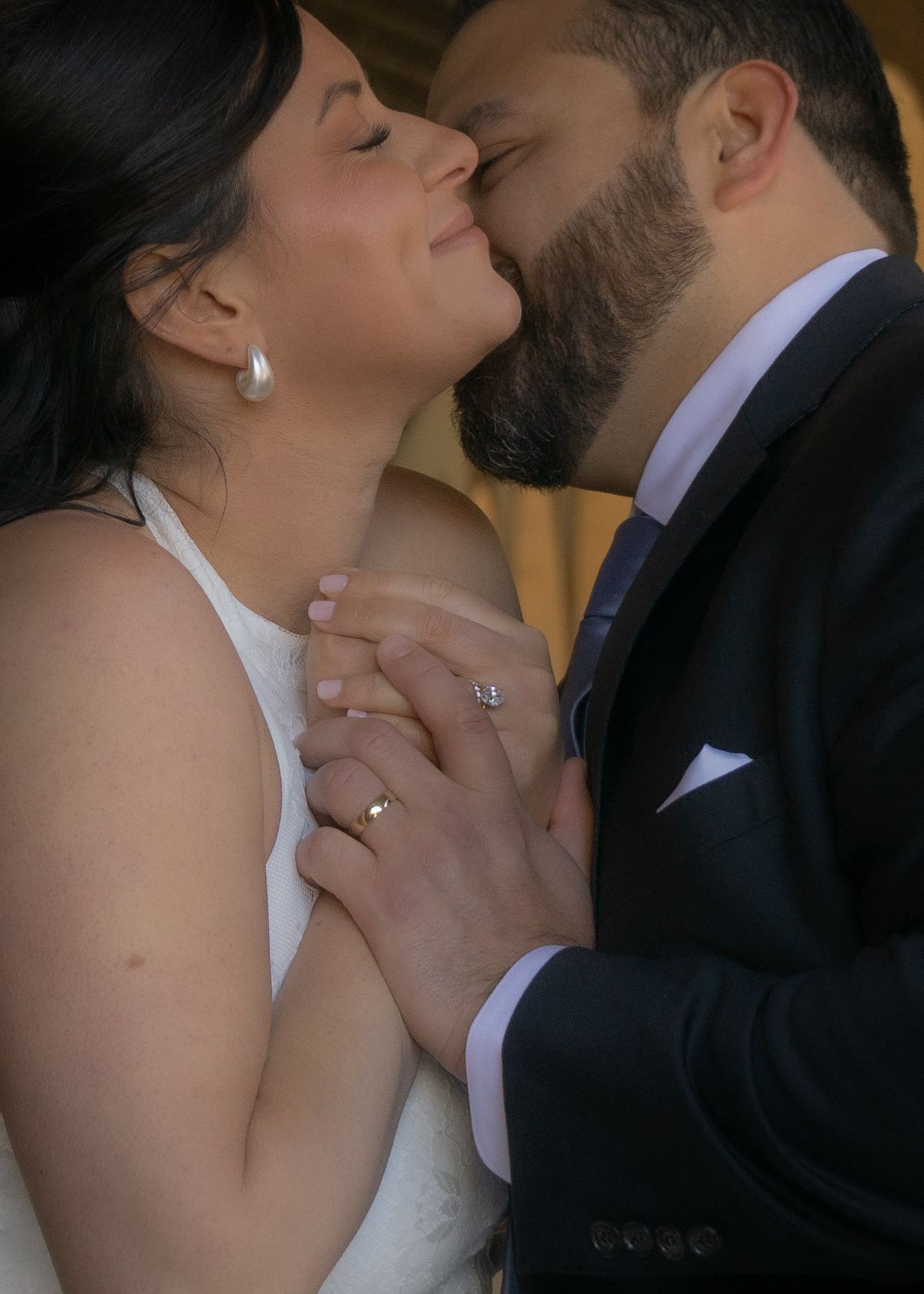 A romantic wedding moment captured as a couple shares a tender kiss while holding hands, with the bride in white.