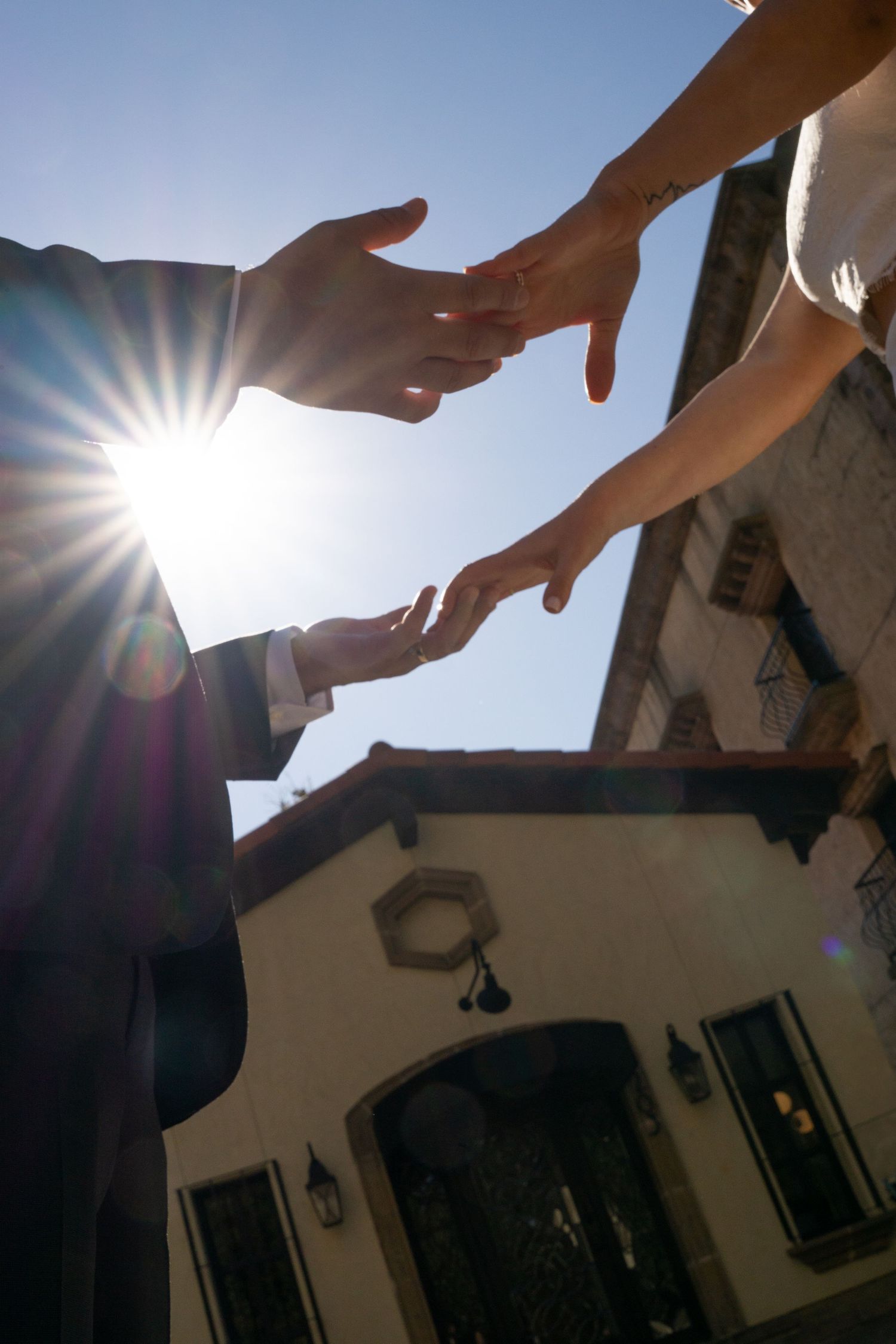 Silhouetted hands reaching towards each other against bright sunlight create a dramatic visual sequence.
