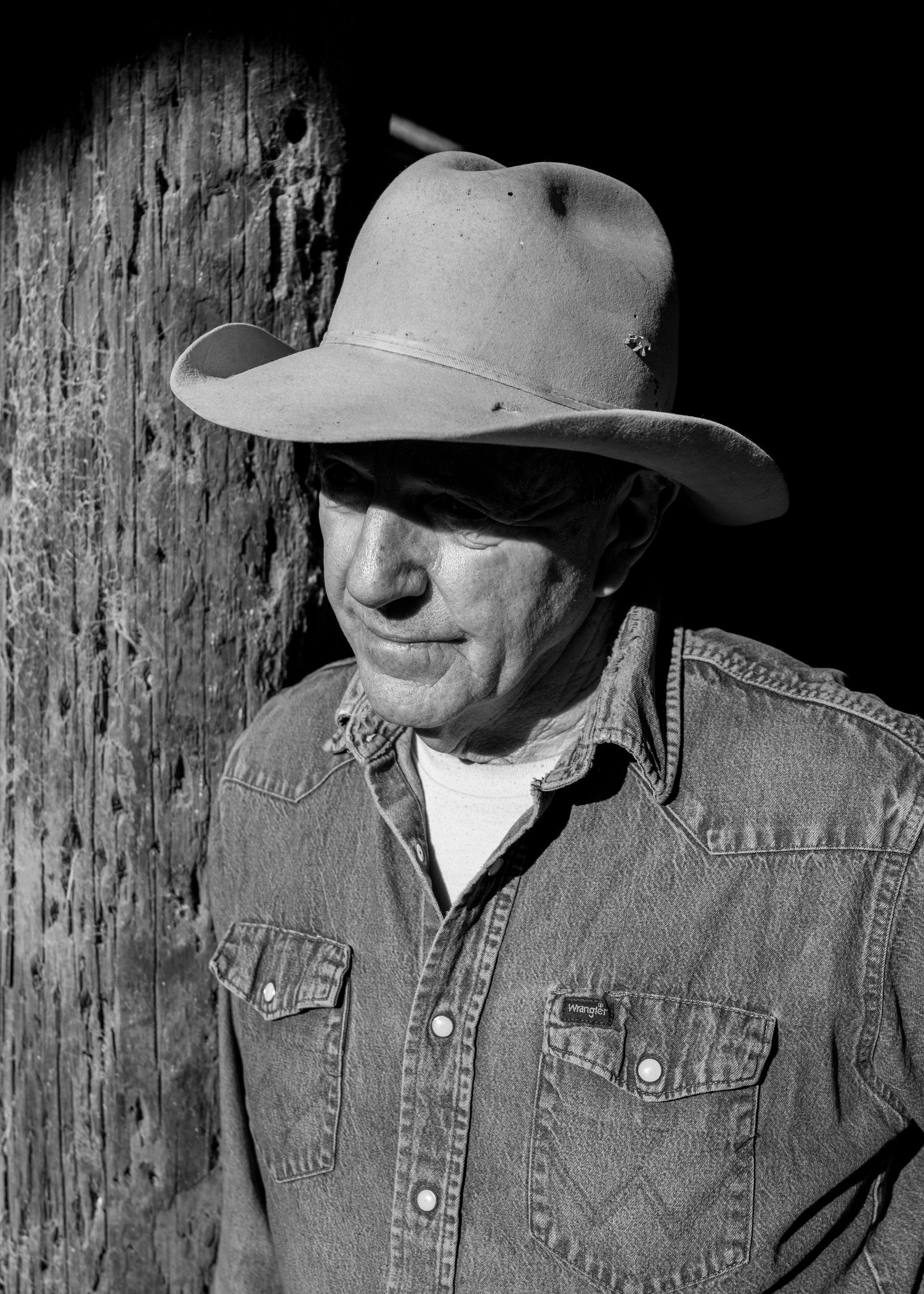 A series of five black and white portraits of a person in a cowboy hat and denim jacket against a dark textured background.