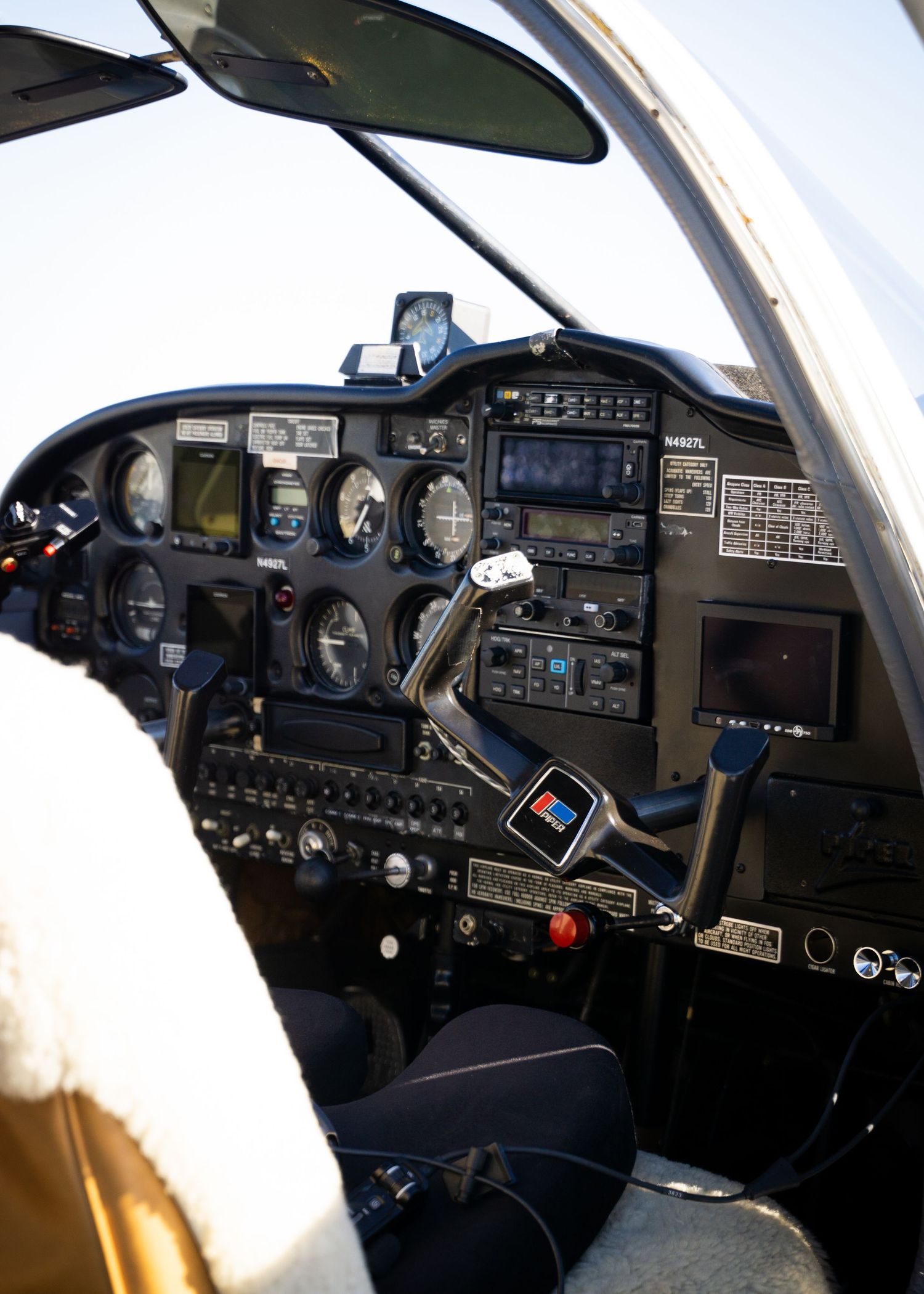 Small aircraft cockpit interior showing flight instruments, avionics panel, controls, and mounted tablet devices.