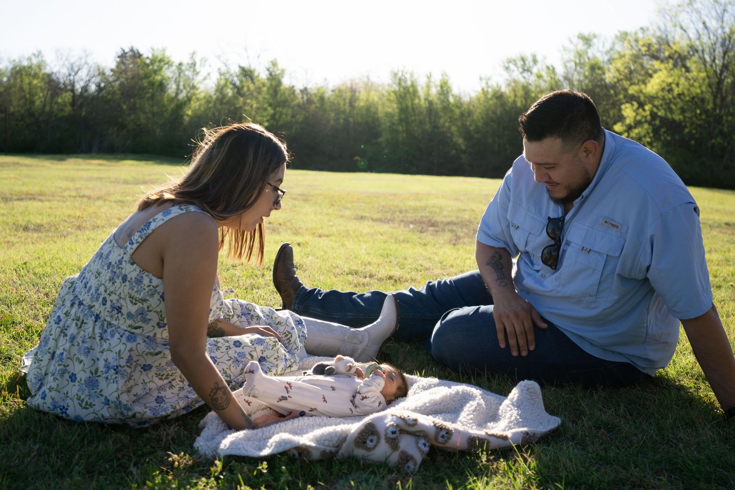 A couple relaxes together on a blanket in a sunny meadow during a warm afternoon.