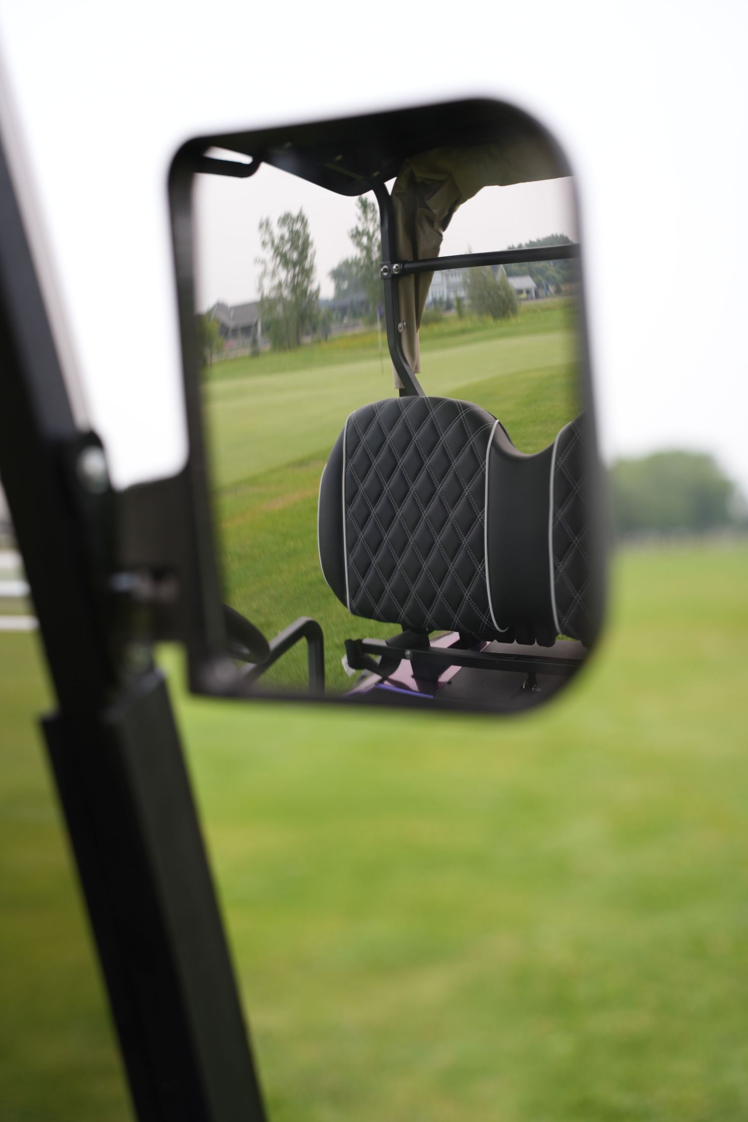 A view of green golf course fairways and rolling hills seen through a vehicle's window.