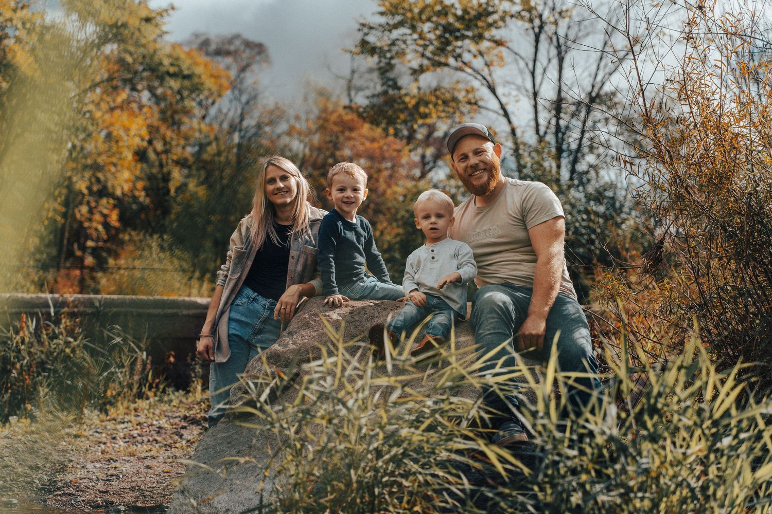 A family enjoys quality time together outdoors during a golden autumn afternoon in a natural setting.