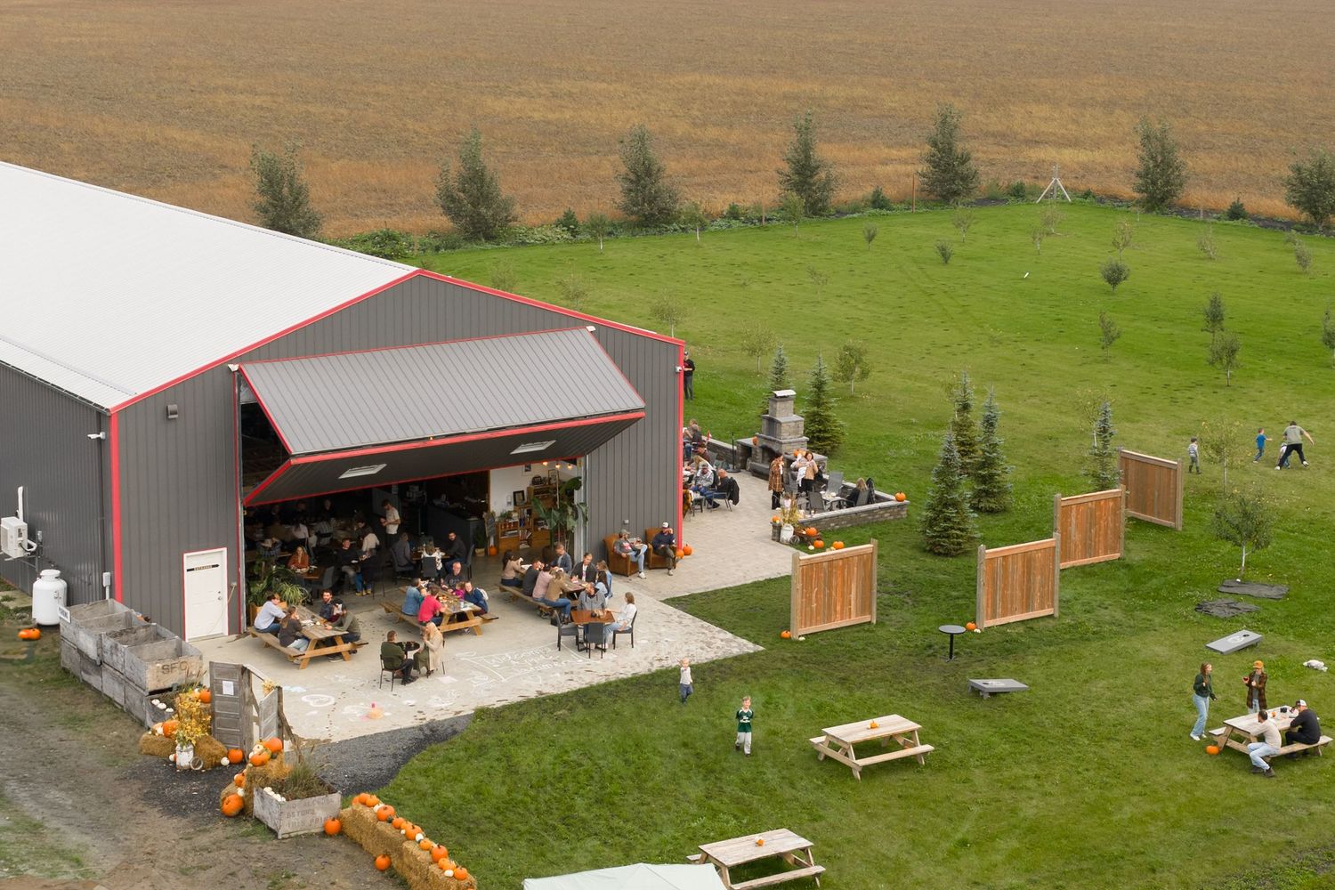 Aerial view of a farm property showing multiple buildings, equipment, and vehicles scattered across green and brown fields.