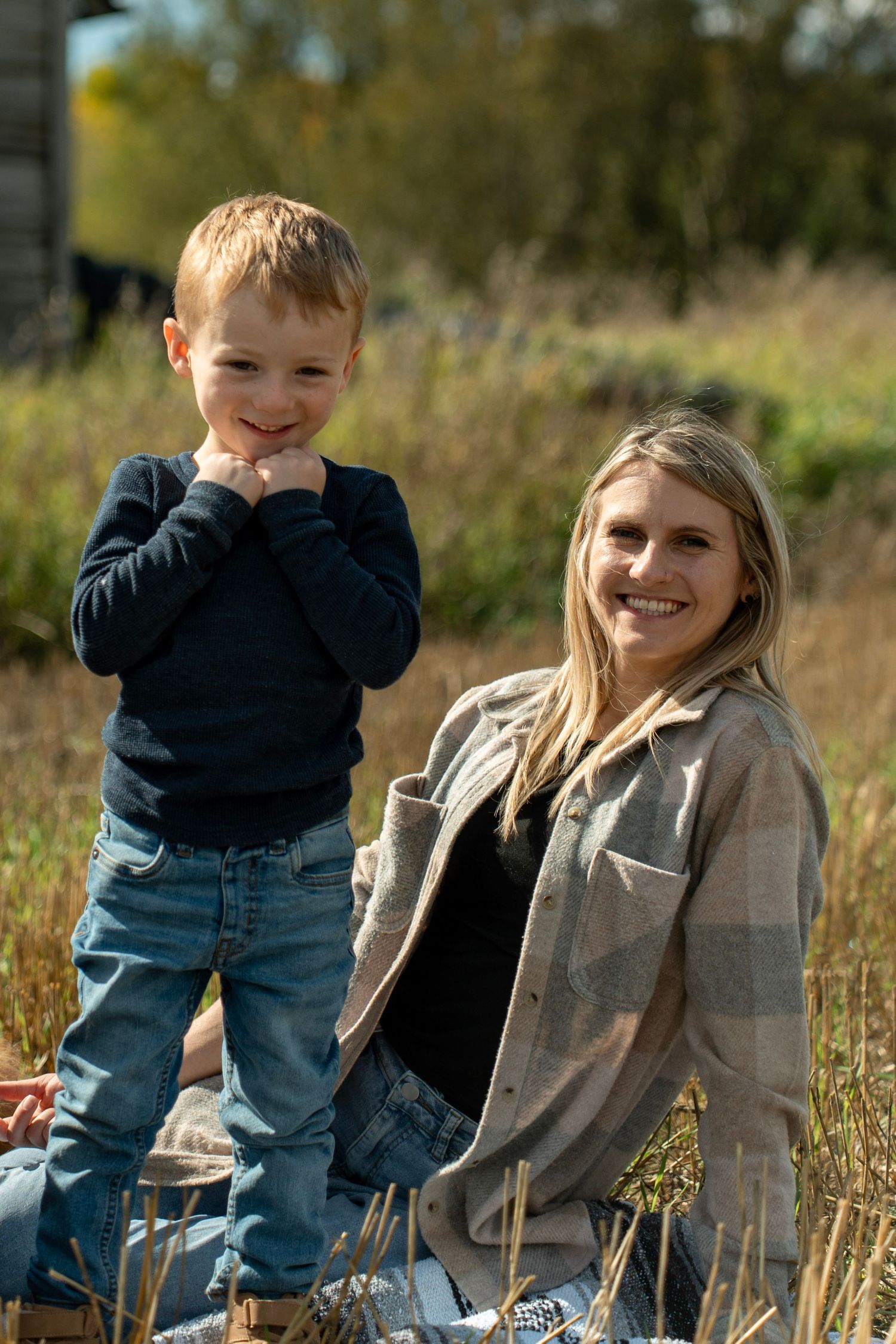 A heartwarming outdoor photo session shows candid moments between two people sitting in a grassy field on a sunny day.