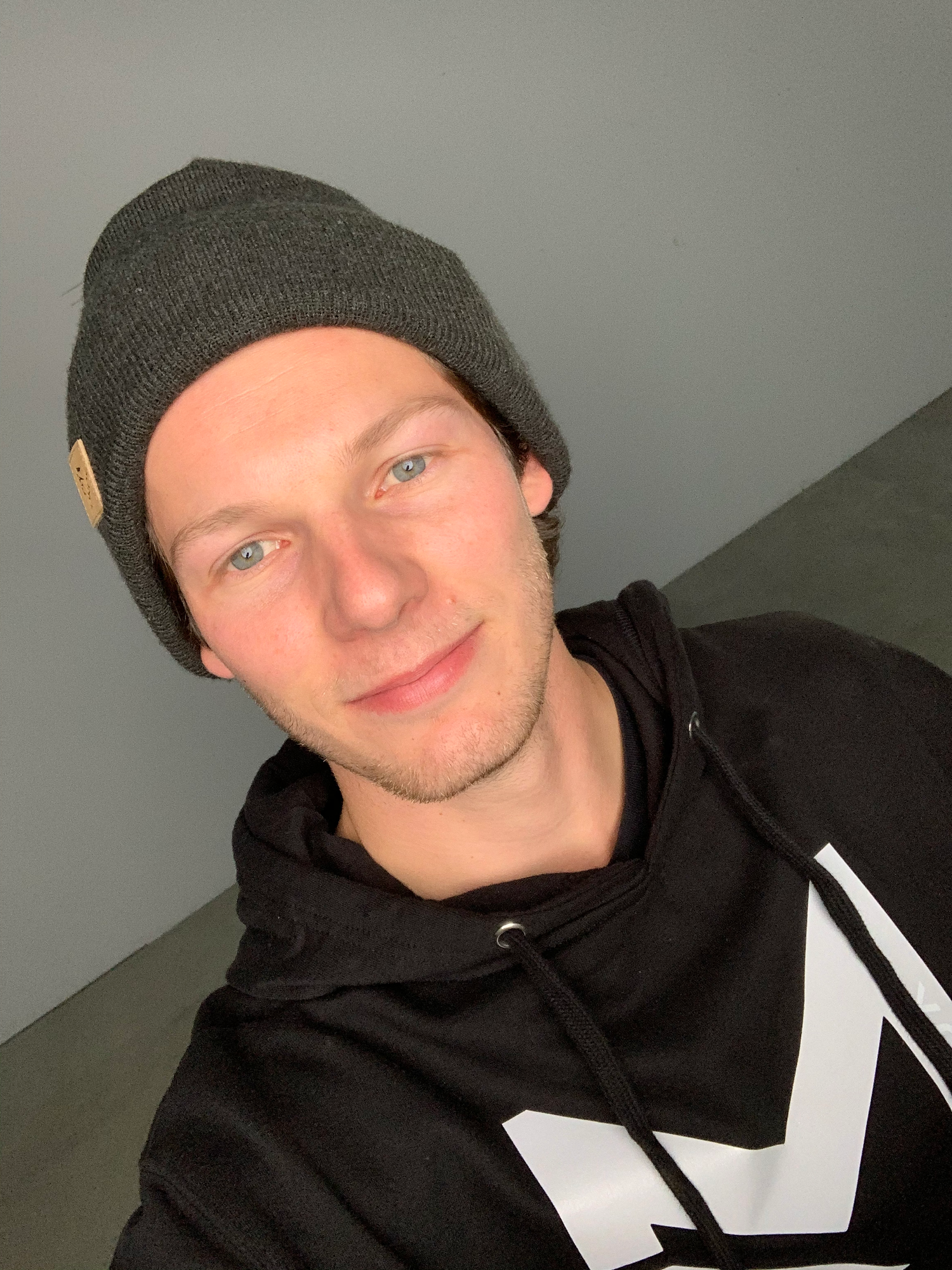 Person wearing a black hoodie and beanie makes a series of playful expressions in selfie collage.