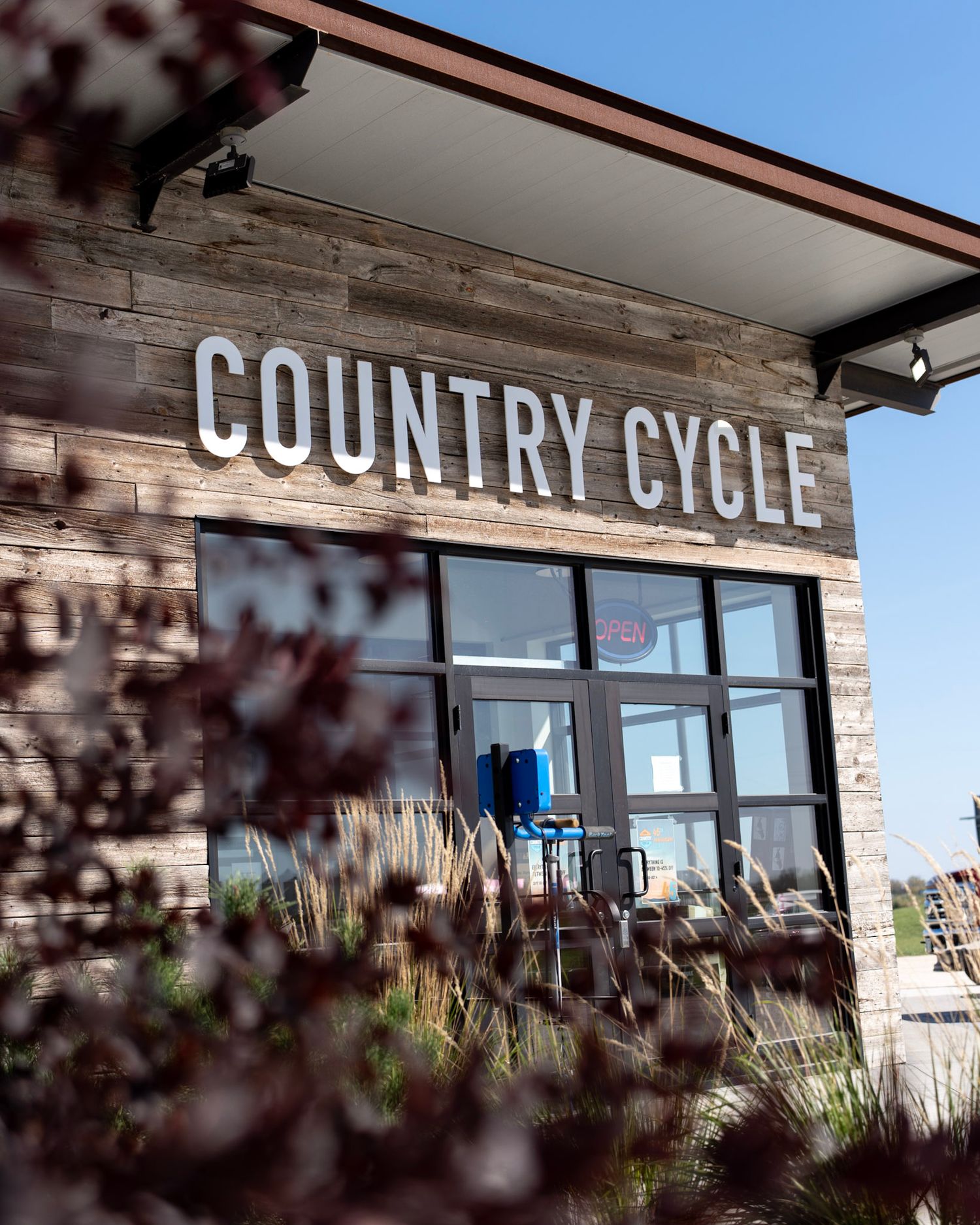 Exterior storefront signage of Country Cycle shop with stone facade and glass windows.