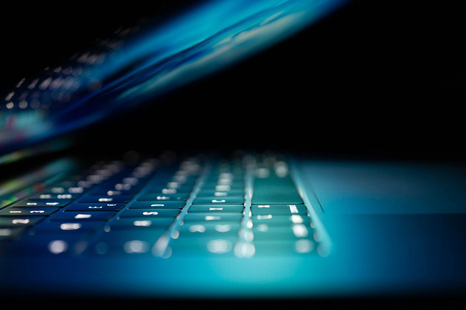 Illuminated computer keyboard keys in blue lighting with motion blur effect creating a dynamic tech atmosphere.