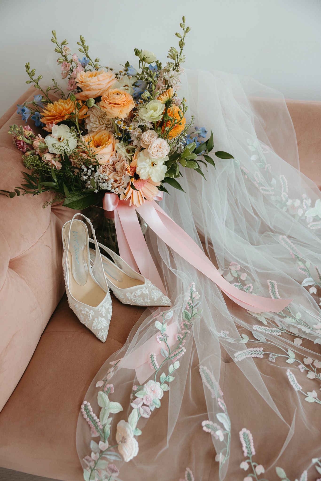 Bridal accessories with peach and white flowers arranged with flowing veil.