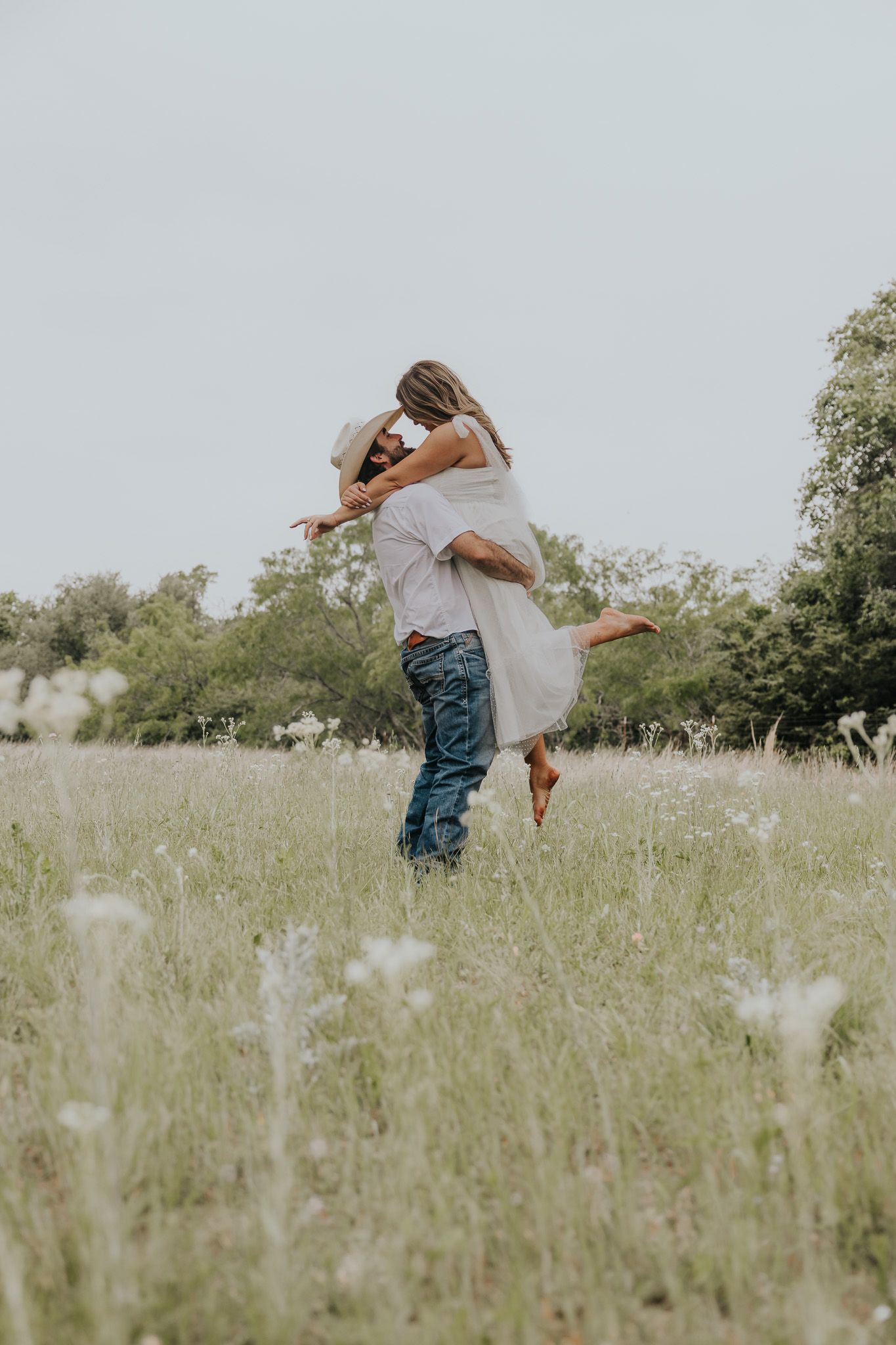 A couple embraces in a romantic spin through a wildflower meadow on a dreamy summer day.