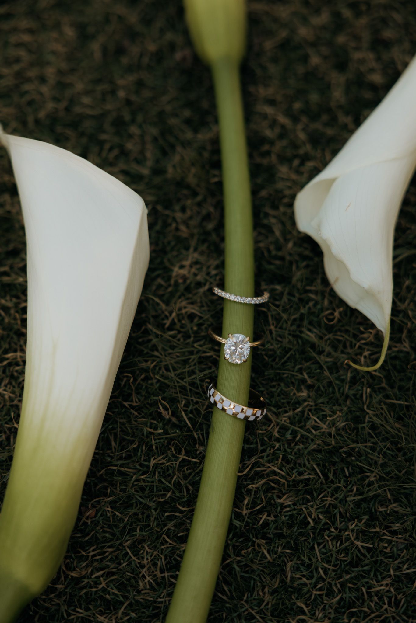 Close-up shots of white calla lilies with diamond rings displayed on their green stems against a dark background.