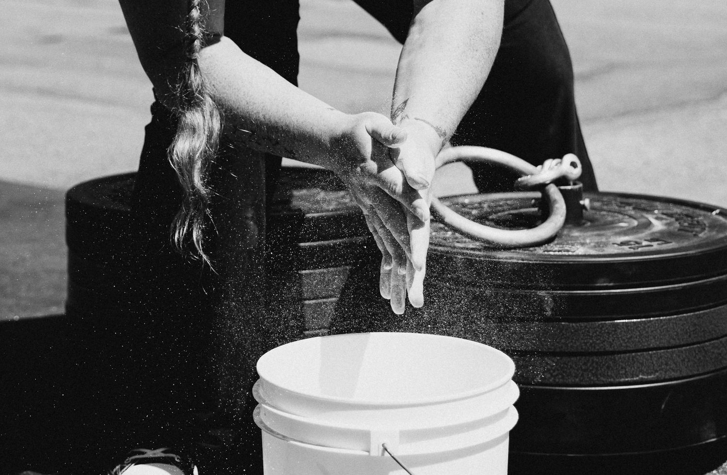 Hands working with beauty products and cosmetic containers in black and white.