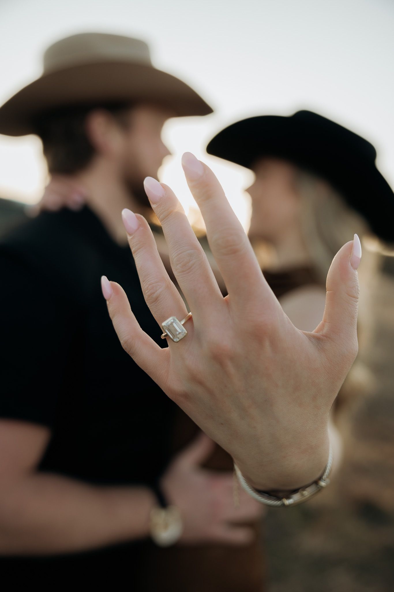 Close-up shot of hands wearing wedding rings against a blurred background.