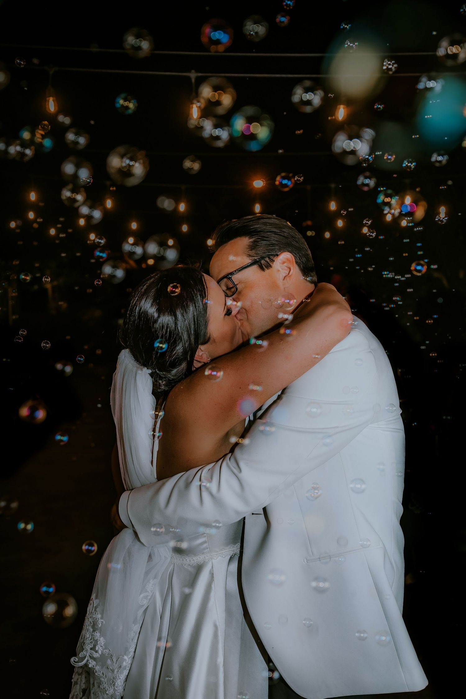 A romantic moment surrounded by floating bubbles creates a dreamy wedding atmosphere.